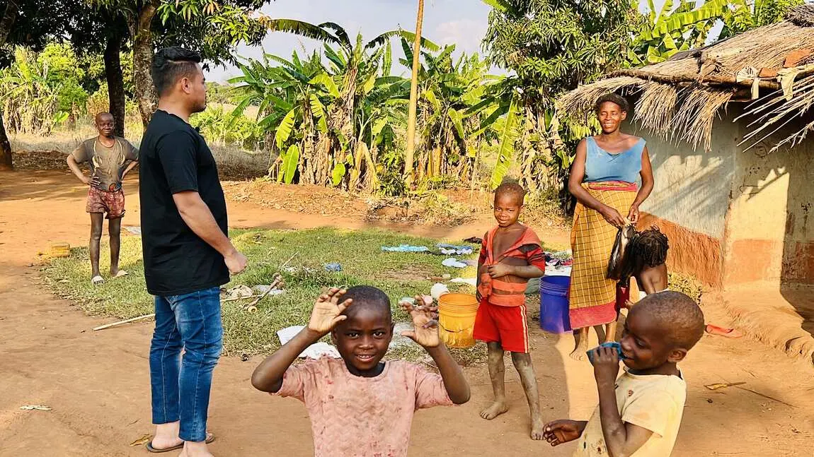 Saif standing with village children among banana trees